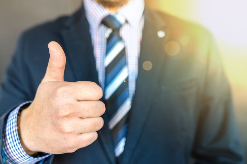 Close-up of a businessman in a suit giving a thumbs-up in a bright, positive setting.